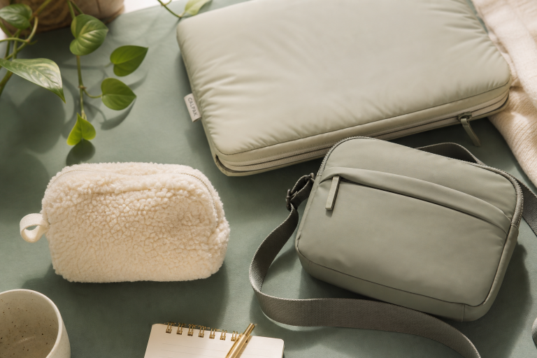 A collection of stylish bags and a notebook on a green surface.