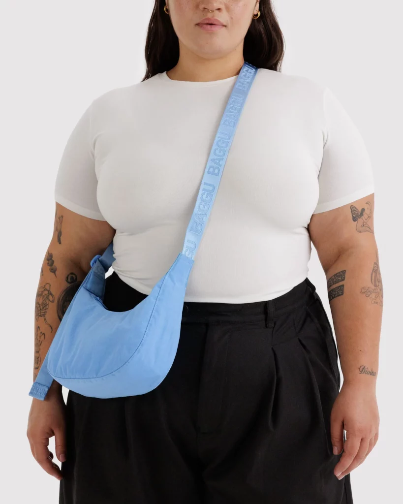 A person wearing a white shirt and black pants, holding a blue bag.