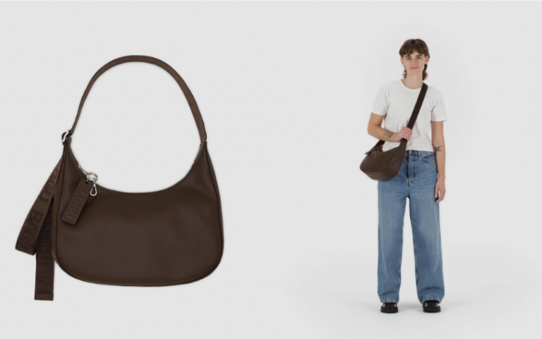 A woman wearing a white t-shirt and blue jeans, holding a brown shoulder bag.