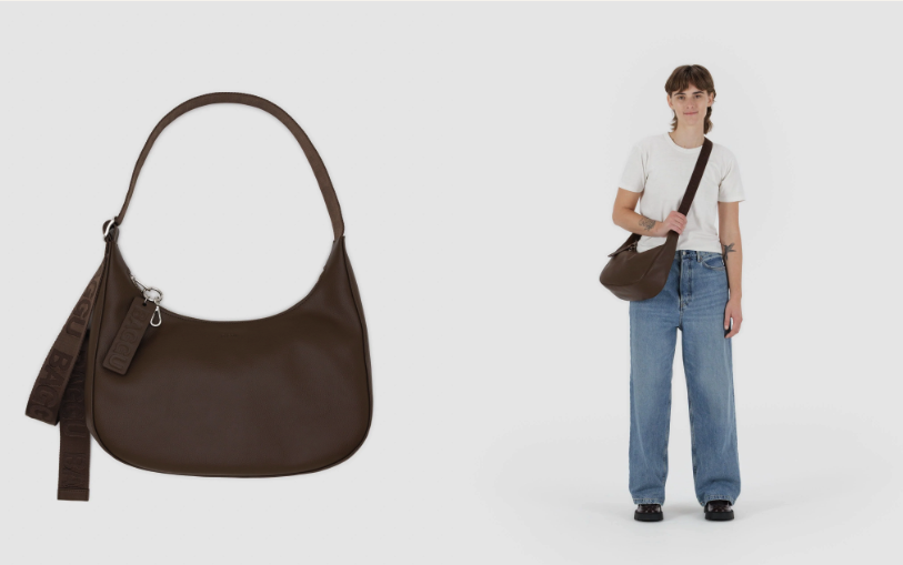 A woman wearing a white t-shirt and blue jeans, holding a brown shoulder bag.