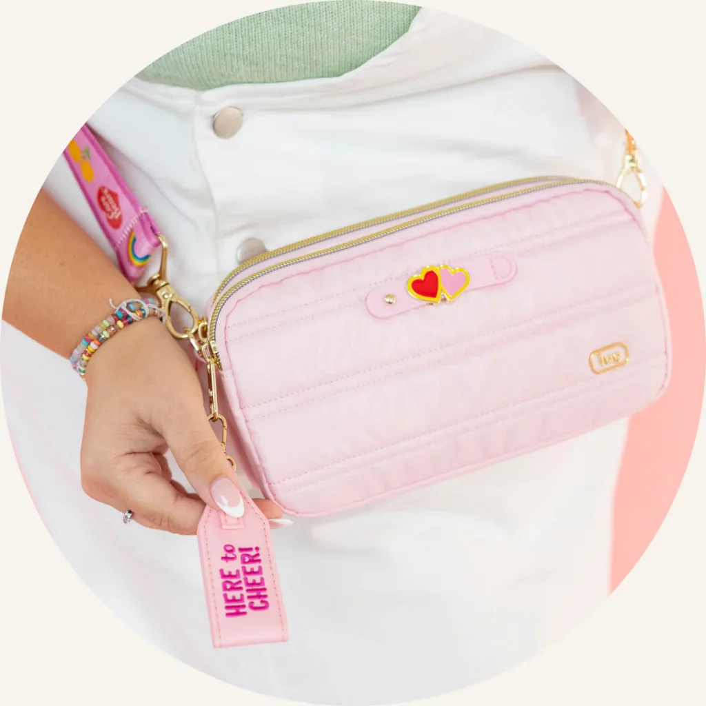 A person holding a pink bag with heart details.