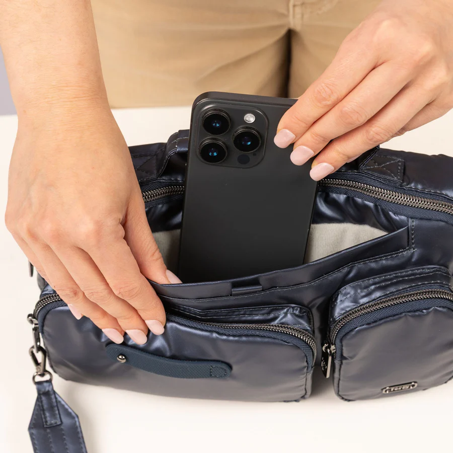 A woman placing a smartphone into a navy bag.